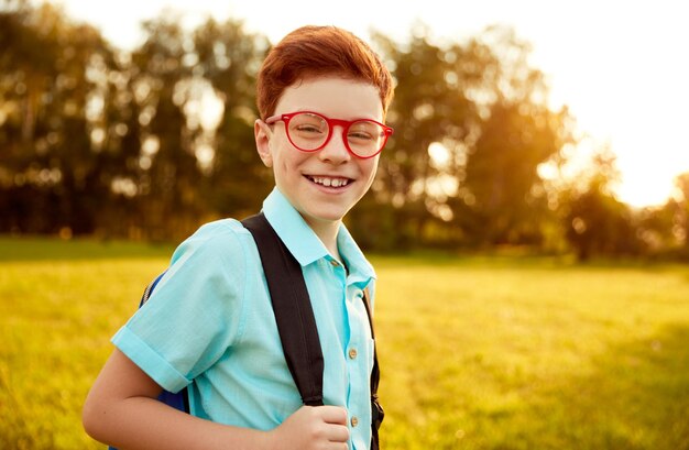 Happy pupil with backpack in park