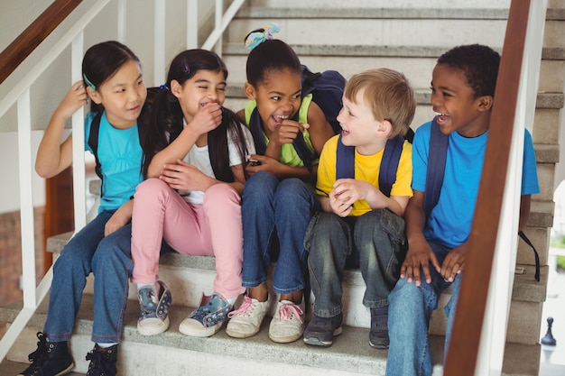 Happy pupils laughing and sitting on stairs