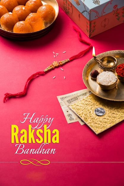 Photo happy raksha bandhan or rakhi greeting card using designer thread, diya, pooja thali, gift box, indian paper currency notes and sweets etc. moody lighting, selective focus