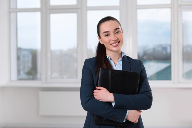 Happy real estate agent with leather portfolio indoors Space for text