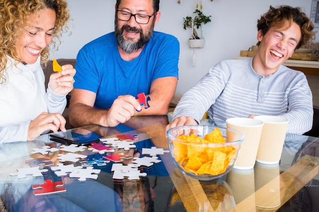 사진 행복한 실제 사람들 가족은 집에서 테이블 위에 있는 카드와 함께 웃고 즐겁게 놀고 있습니다. 남자와 여자 아버지 어머니, 아들과 함께 일요일 휴일에 장난스러운 실내 여가 활동을 즐기며 시간을 보냅니다