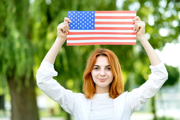 Foto felice ragazza dai capelli rossi in posa con la bandiera nazionale usa