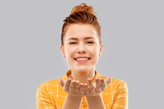 Photo happy red haired teenage girl holding empty hands