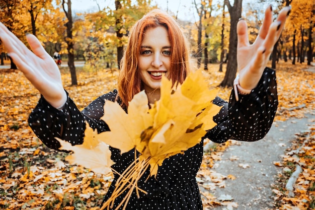 노란 단풍을 들고 행복한 redhaired 여자 가을 공원에서 단풍