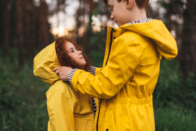 Happy redhead boy and girl in raincoats