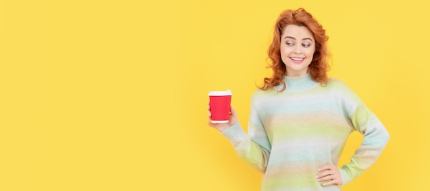 Happy redhead woman drink takeaway coffee from cup on yellow background morning coffee Woman