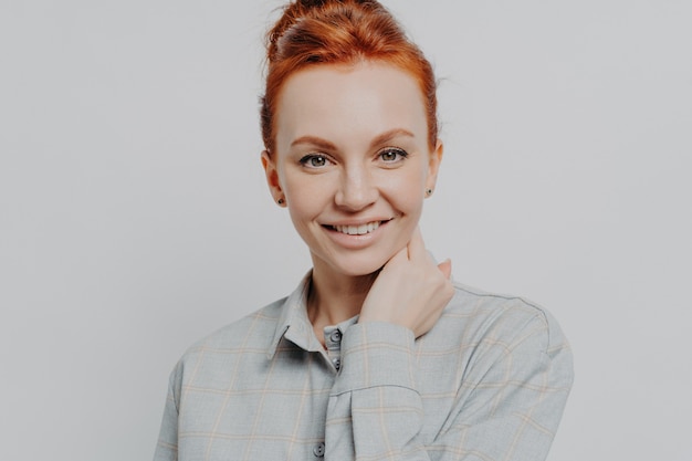 Happy redhead woman looking at camera white toothy smile isolated over grey background