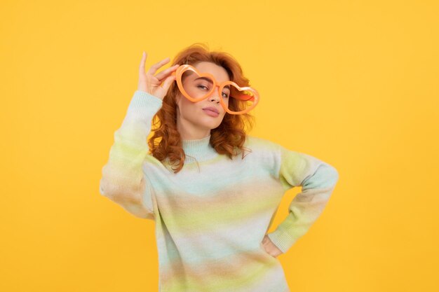 Happy redhead woman wear funny party glasses on yellow background party fun