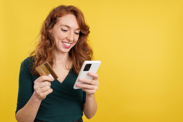 Happy redheaded woman shopping online with the mobile