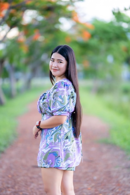 Happy Relaxing Portrait asian woman Wear purple dress wearing smartwatch while lawn beside a reservoir at the city park outdoors