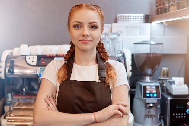 Happy restaurant manager with folded hands looking directly at camera