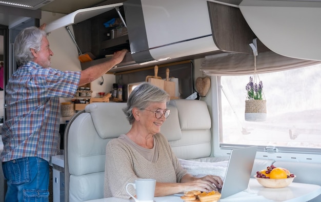 Happy retired caucasian couple enjoying freedom and alternative lifestyle traveling in camper van