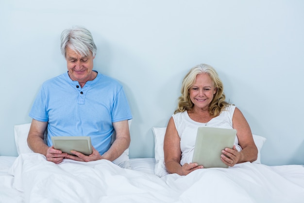 Happy retired couple using digital tablets