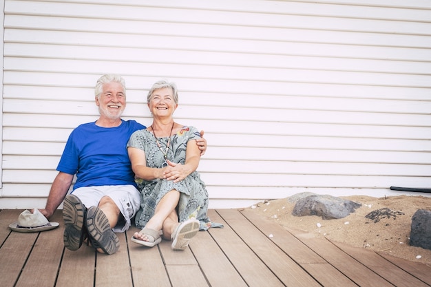 Photo happy retired lifestyle concept with aged senior man and woman sitting on the wooden ground and smile together with happiness and joy. cheerful mature people enjoy together life with hug and love