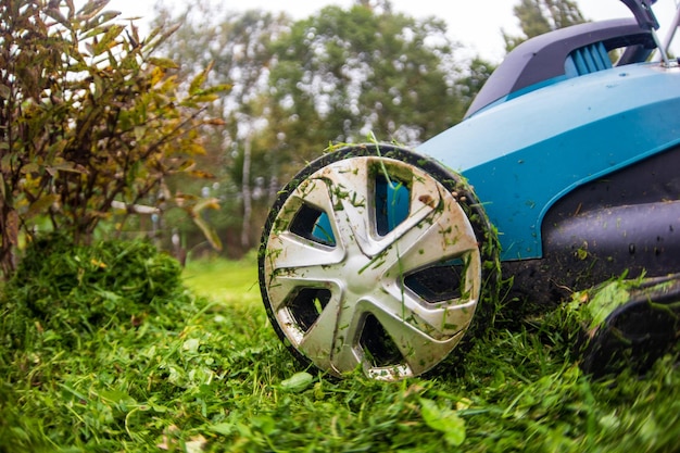 행복한 은퇴한 노인은 잔디 깎는 기계로 정원에서 잔디를 깎습니다.