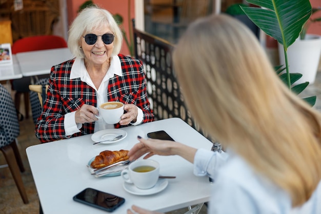 Счастливая пенсионерка, пьющая кофе в уличном кафе