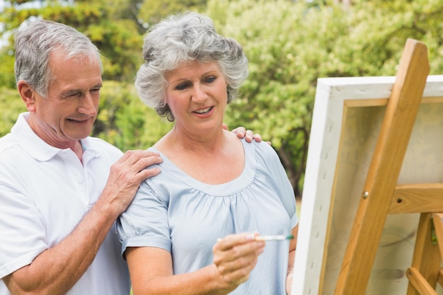 幸せな引退の女性キャンバスに絵を描くと夫と話す