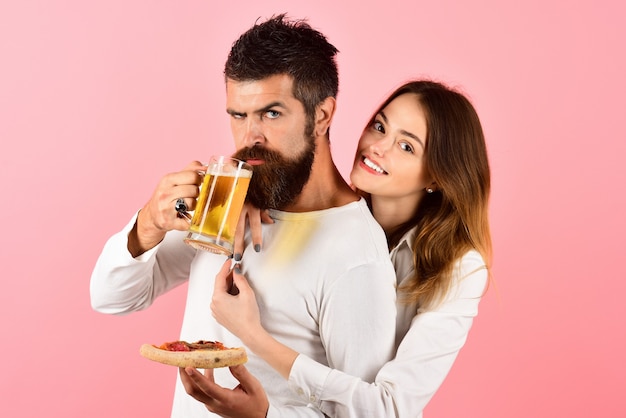 Happy romantic couple eating pizza drinks beer loving couple enjoy yummy pizza pretty young girl