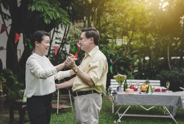 Happy romantic senior couple dancing at home garden