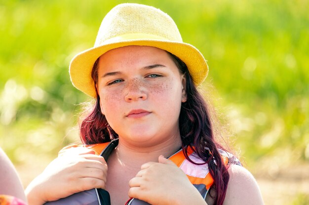 救命胴衣と帽子をかぶった幸せなロシアの女の子が夏のボートに乗る準備をしています