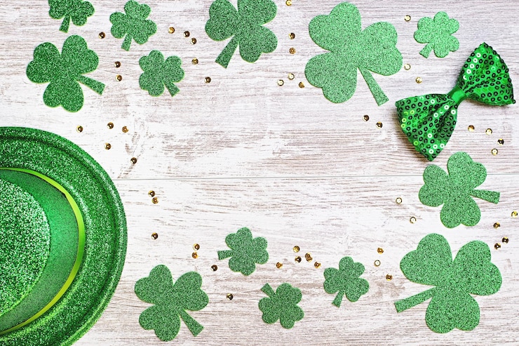 Photo happy saint patrick's day greeting card with traditional symbols, shamrock, green attire. green hat, bow tie, st patricks day shamrocks, golden confetti on wooden background, copy space, top view