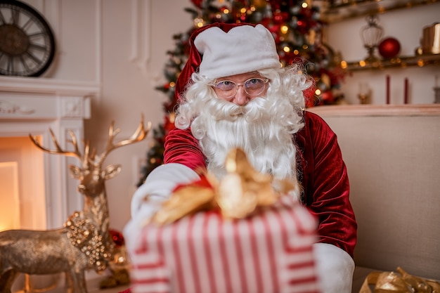 幸せなサンタクロースは子供たちに贈り物をもたらしました。新年とメリークリスマスの休日のコンセプト