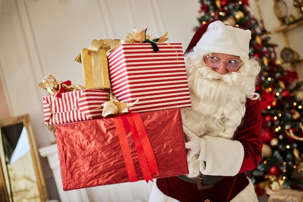 幸せなサンタ クロースは子供たちに多くの贈り物をもたらした新年とメリー クリスマスの休日の概念