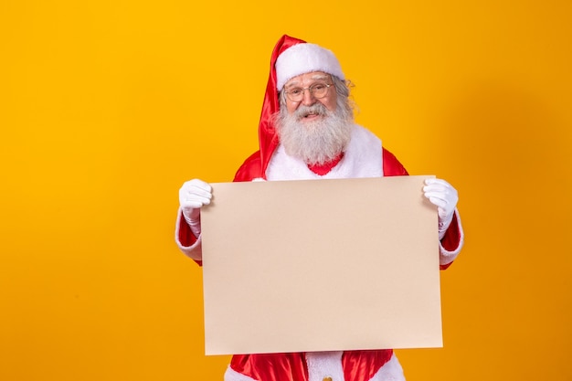 Happy Santa Claus holding a blank board isolated on yellow background with copy space.