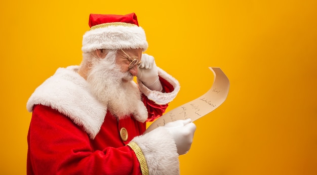 Happy Santa Claus holding vintage paper on yellow