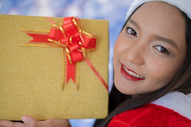 Foto happy santa claus-meisje houdt de huidige doos met sneeuwachtergrond vast.
