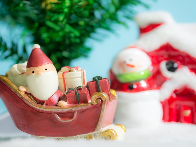 Happy Santa Claus with gifts box on the snow sled going to house.