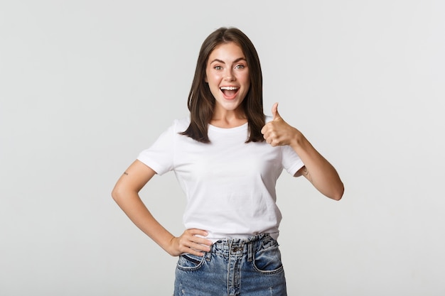 Happy satisfied young woman smiling, showing thumbs-up in approval, like something.