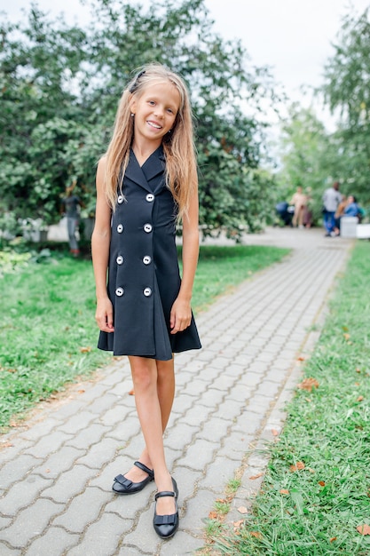 Ragazza felice della scuola che posa nei ourdoors della scuola