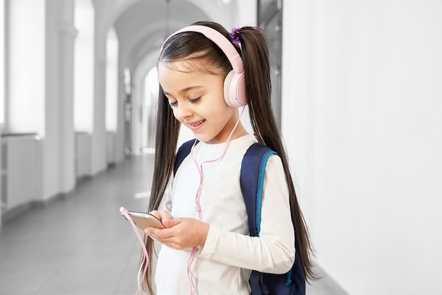 Happy school girl using smartphone and listening music