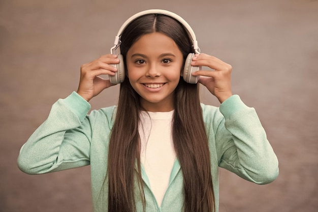 Счастливый школьник слушает музыку или аудиокнигу в наушниках для образования и радости детства