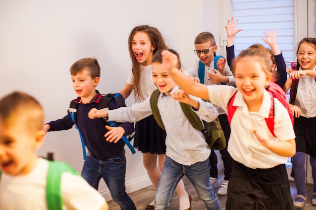 Happy school kids running in elementary school hallway front view