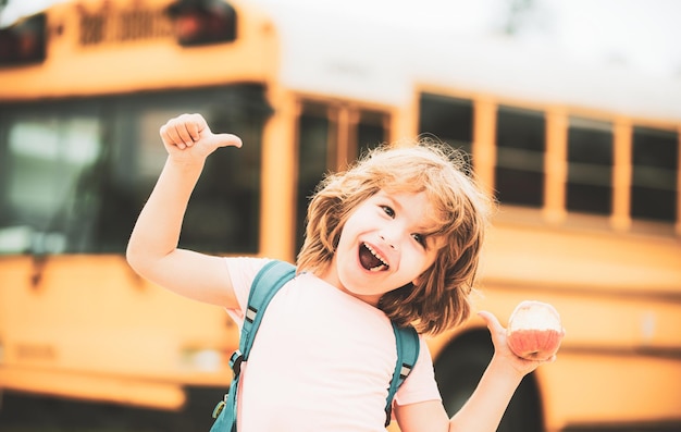Bambini felici della scuola sullo scuolabus thumbs up del bambino sorridente e felice