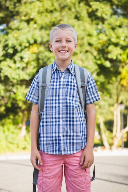 Happy schoolboy standing in campus