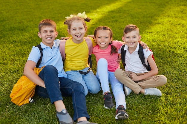 Happy schoolchildren on lawn in park