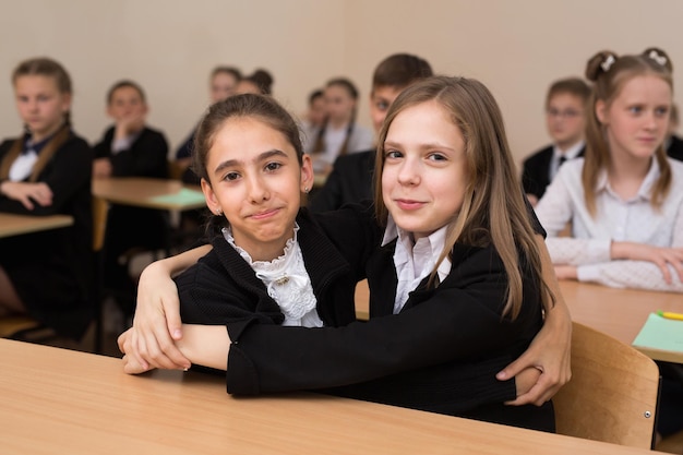 Happy schoolchildren sit at a desk in the classroom