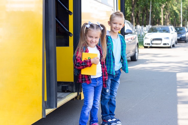 Foto scolari felici con gli zaini scendono dallo scuolabus.