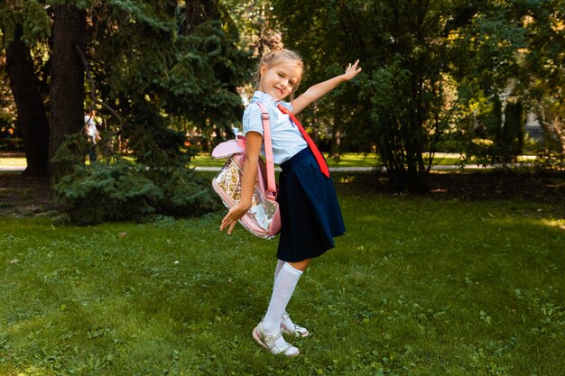 Happy schoolgirl holding a book outdoors. A small child goes to school. Copy space.