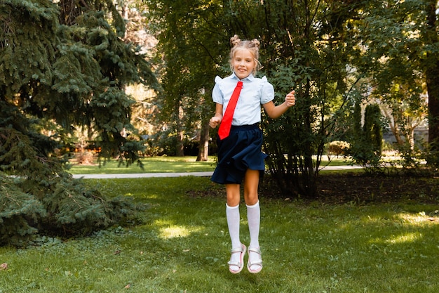 Happy schoolgirl holding a book outdoors. A small child goes to school. Copy space.