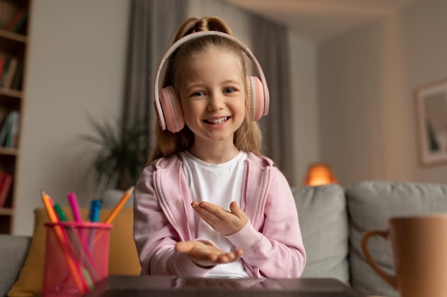 Happy schoolgirl talking to laptop webcamera video calling at home