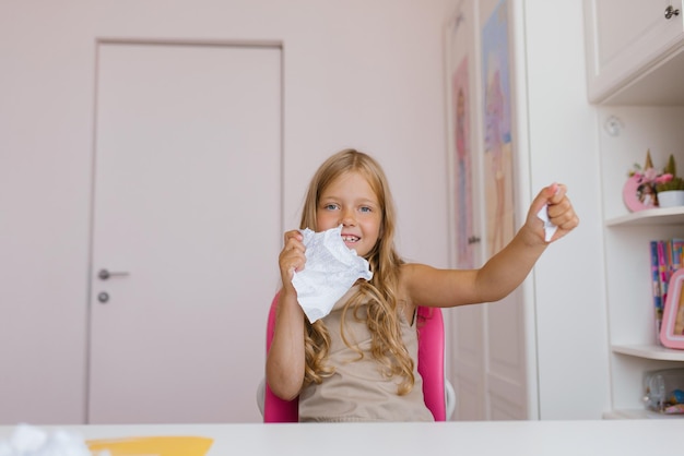 Happy schoolgirl tears up a sheet of a school notebook because of an incorrectly completed homework assignment