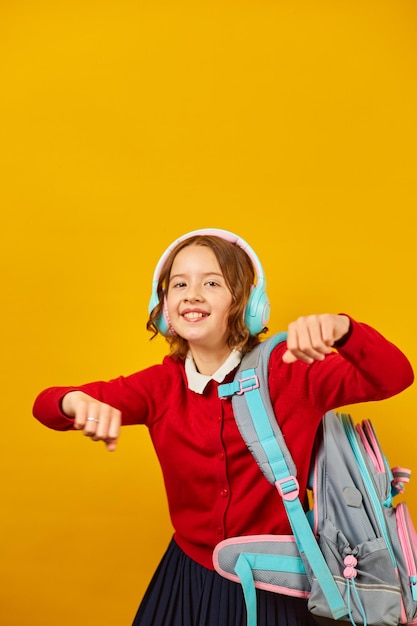 Happy schoolgirl with backpack headphone having fun