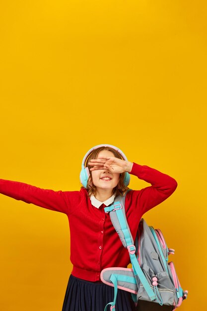 Happy schoolgirl with backpack headphone having fun