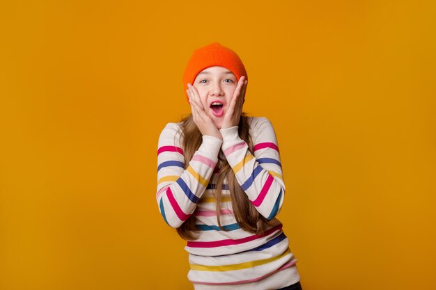 Photo happy schoolgirl with long hair holds her hands in front on a yellow background