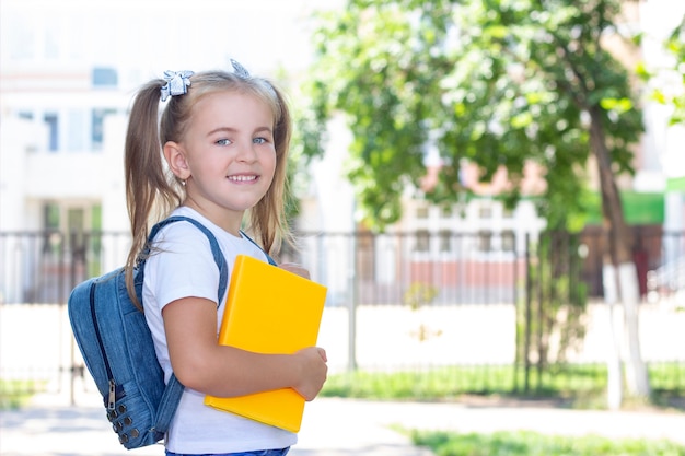 Happy schoolgirl with a textbook in her hands.