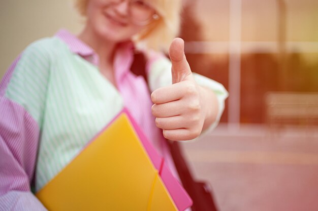 Happy sdudent showing thumb up and holding her folders